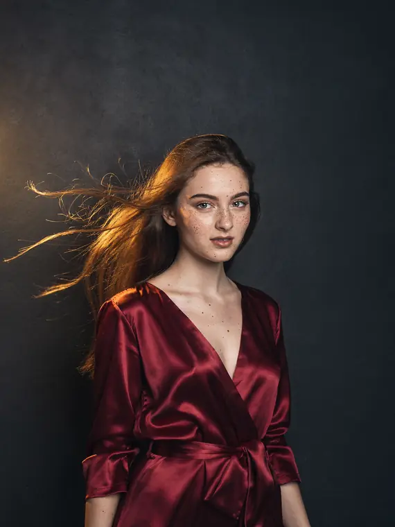 Photoreal portrait of a woman in a red silk dress against a dark charcoal wall